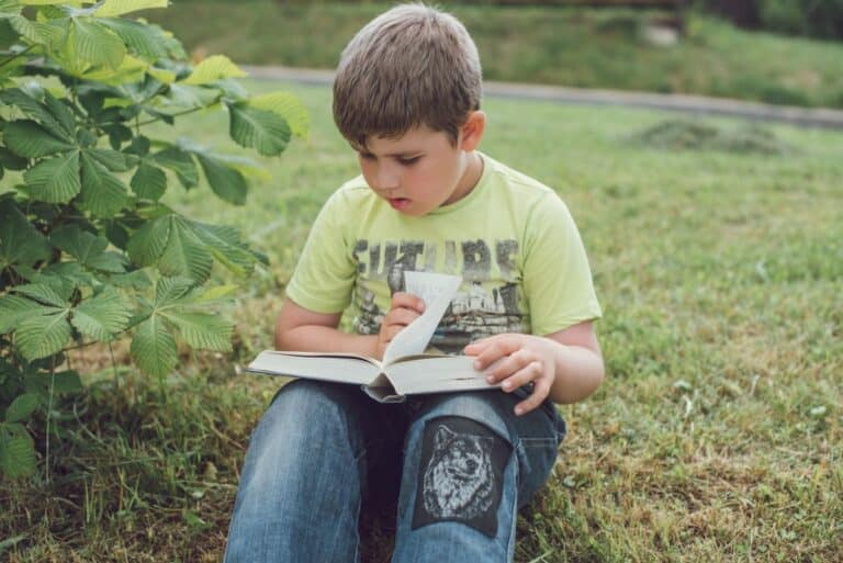 Child reading a book outdoors in summer - summer reading activities KS2