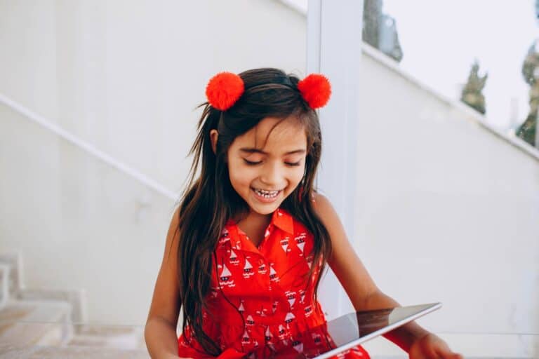 Happy KS2 child smiling while using a tablet outdoors, following screen time rules during the summer holidays