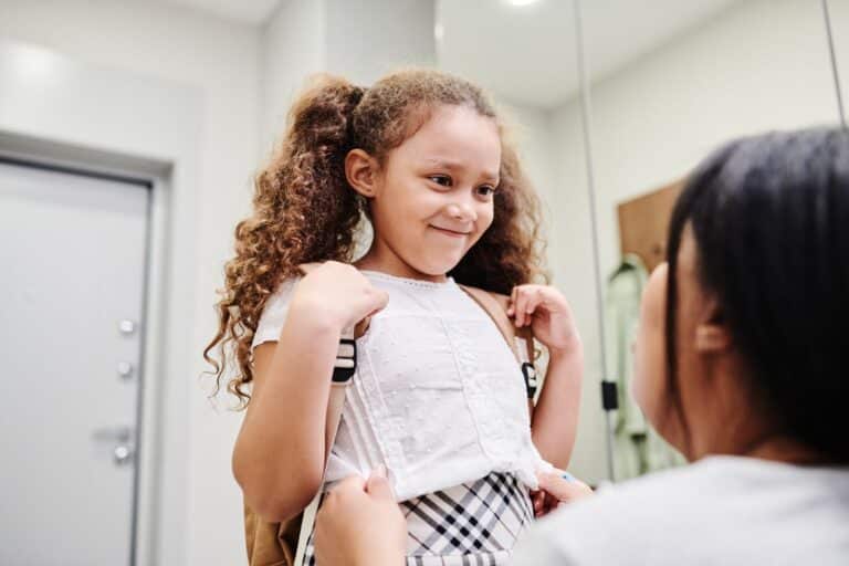 Girl getting ready in the morning as part of a back to school routine, smiling at her mum